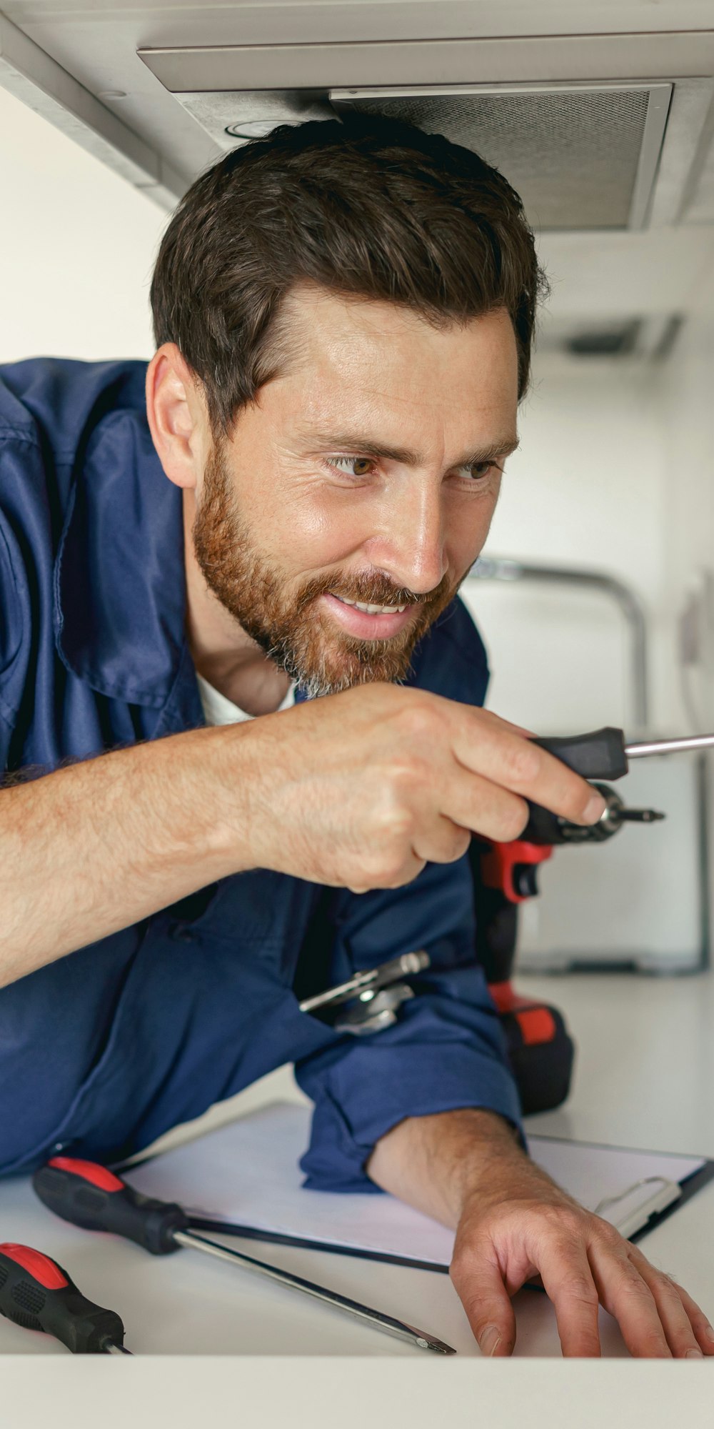 Professional electrician using screwdriver while installing new electrical socket on home kitchen